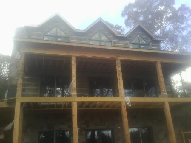 Dormers and porch framing on a large log home under construction — Roof Coating work by our crew in Little Suamico