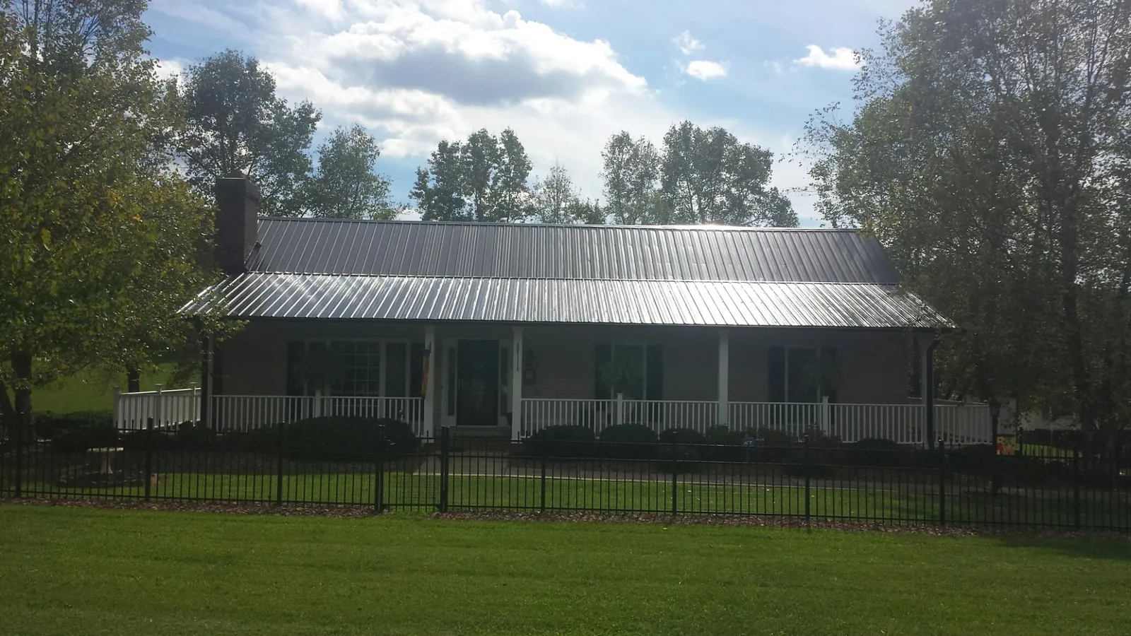 Gray metal roof on a brick ranch with a full width front porch — Gutter Guard Installation work by our crew in Little Suamico