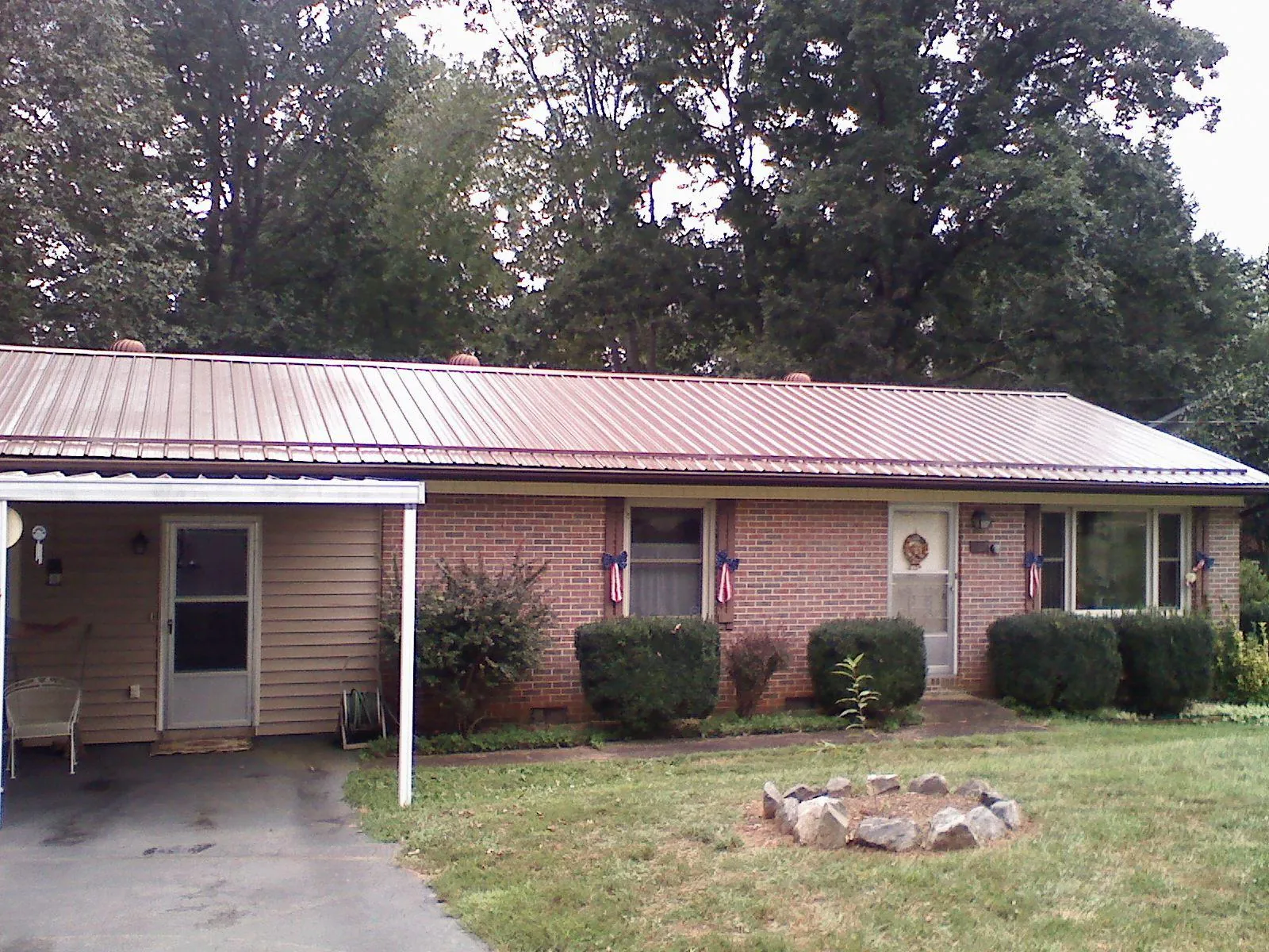 Bronze metal roof and carport on a brick ranch home — Roof Repair work by our crew in Little Suamico