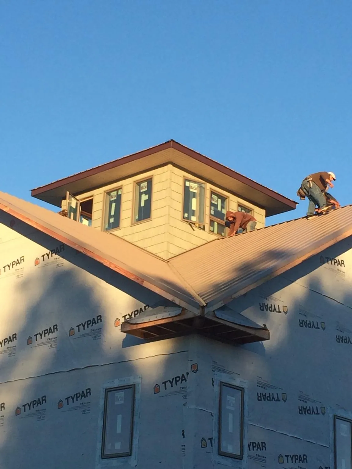 Roofers working around a rooftop cupola on a new metal roof at sunset — Roof Waterproofing in Little Suamico by Roofing Brothers